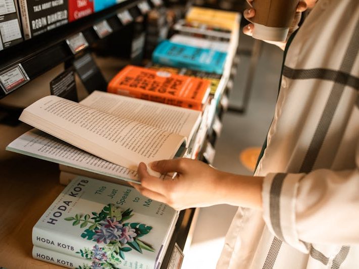  A person browsing through books or holding a selection of books, possibly at a bookstore or library.